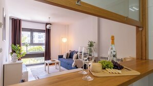 Un salon moderne avec un canapé, une petite table, un verre de vin, une bouteille de champagne et un assortiment de fruits.