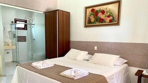 Habitación de hotel con cama, armario, ducha y un cuadro en la pared.
