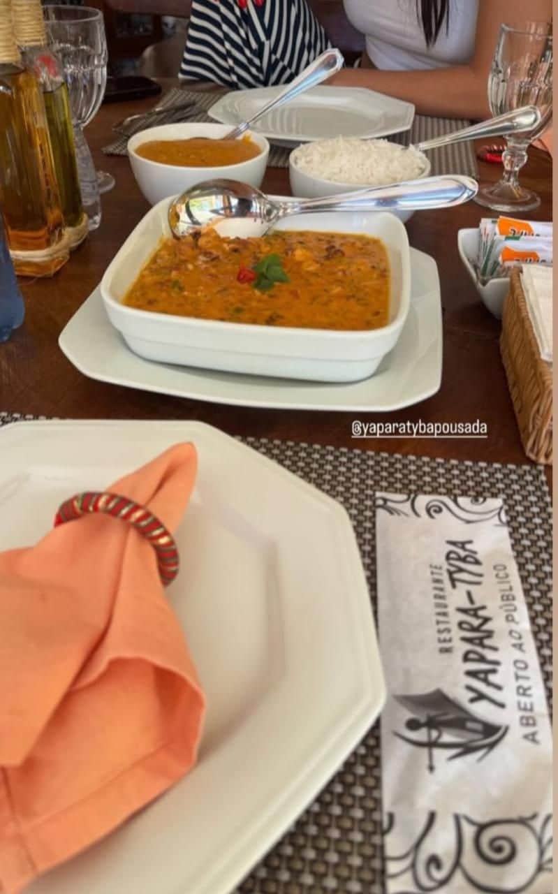 Uma mesa de jantar com um prato branco, uma tigela de sopa e um pacote de arroz.