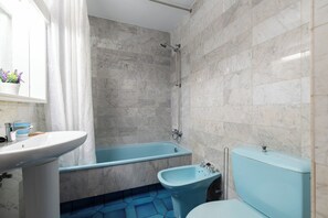 Une salle de bain avec une baignoire, un bidet et des toilettes.