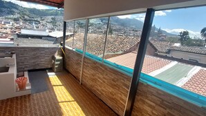 A balcony with a view of a cityscape, a small sink, and a trash bin.