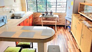 A compact kitchen with a large window, wooden cabinets, and a dining area with a table and chairs.