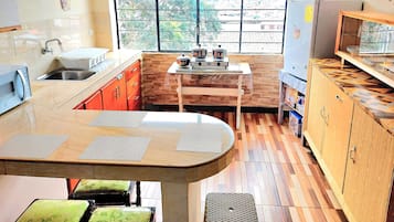 Een koelkast, een magnetron, een blender, kookgerei, borden en bestek