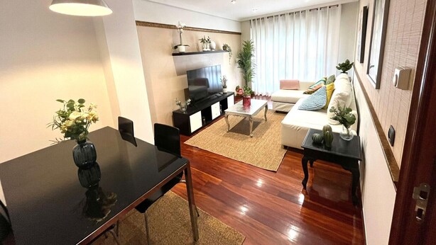 A modern living room with a dining table, sofa, and TV. - Olive Apartment with Parking (Vigo)