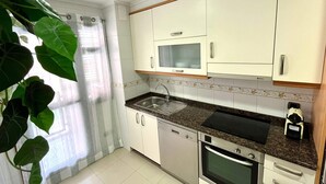 A compact kitchen with white cabinets, a microwave, a dishwasher, and an oven. - Olive Apartment with Parking (Vigo)