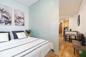 Un dormitorio moderno con cama, mesitas de noche y una pequeña zona de escritorio con una silla.