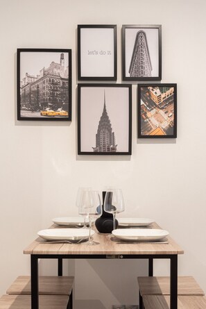 A dining table with framed cityscape photographs, two wine glasses, and plates. - Precioso Loft Puerto Maritimo with Parking (Vigo)