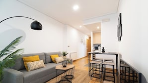 A modern living room with a grey sofa, a coffee table, and a dining area with stools. - Precioso Loft Puerto Maritimo with Parking (Vigo)