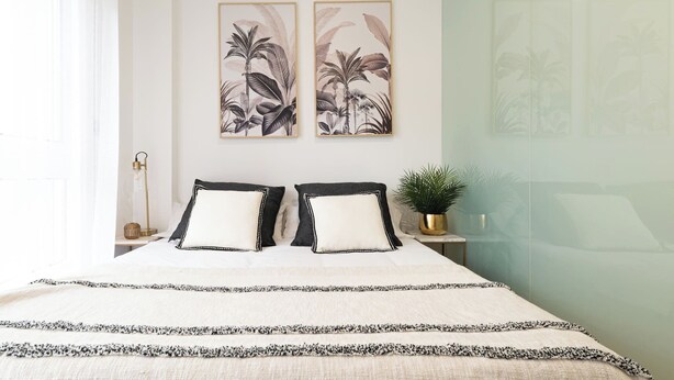 A bedroom with a bed, two pillows, a bedside table with a lamp, and a wall-mounted plant. - Precioso Loft Puerto Maritimo with Parking (Vigo)