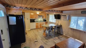 Eine kompakte Küche mit Holzausstattung, einem Kühlschrank, einer Mikrowelle und einem Essbereich mit Tisch und Stühlen.