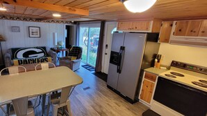 Eine kompakte Küche mit Essbereich, inklusive Kühlschrank, Herd und Tisch mit Stühlen.