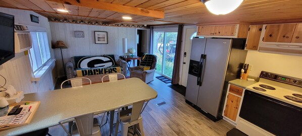 A compact kitchen with a dining area, featuring a refrigerator, stove, and a table with chairs.