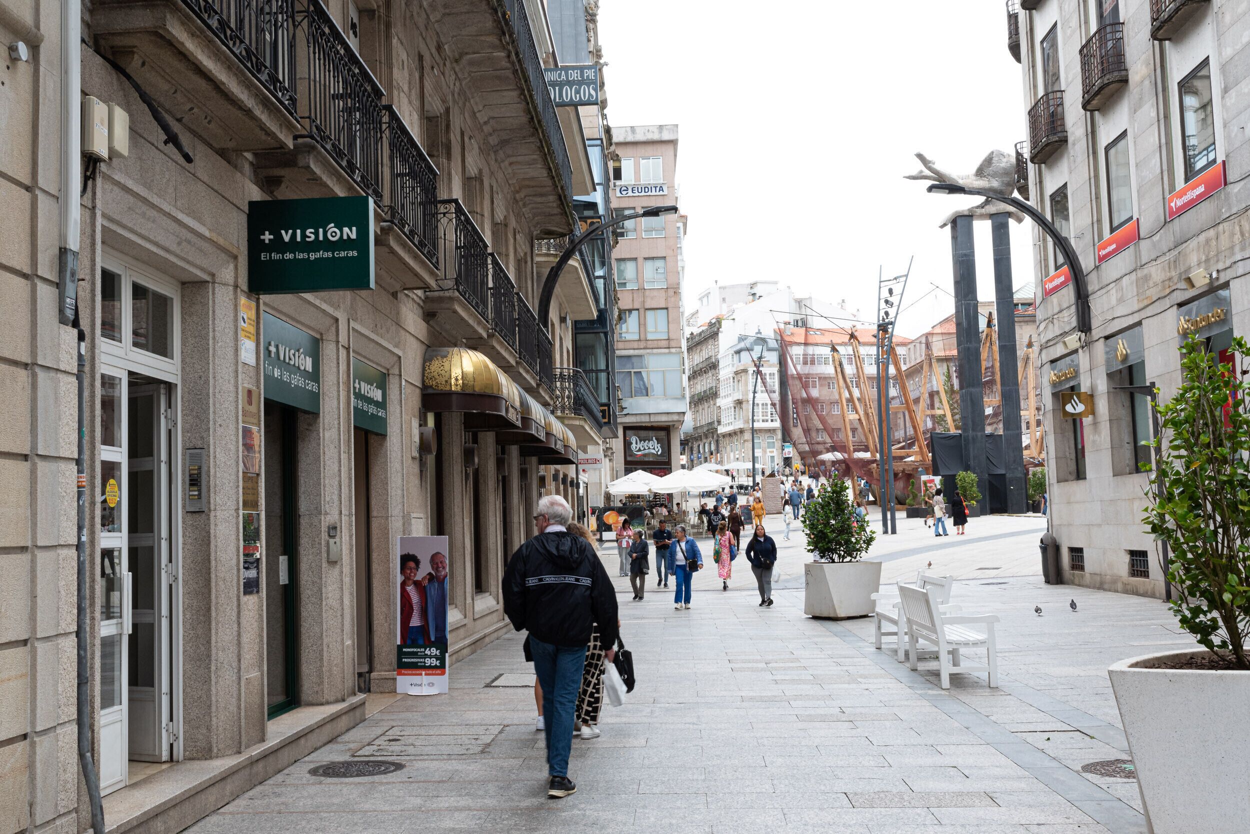 A pedestrian street with shops, benches, and outdoor seating.