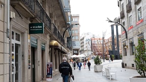 Una calle peatonal con comercios, bancos y terrazas.