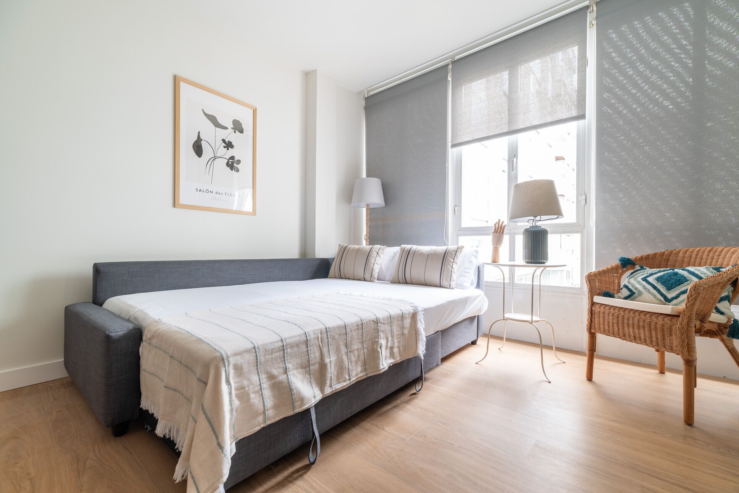 A bedroom with a bed, a chair, a window with a view, and a wall with a framed picture.