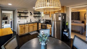 Et moderne køkken med træskabe, et rustfrit stål køleskab og et spiseområde med et rundt bord og stole.