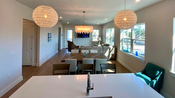 A spacious kitchen with a central island, pendant lights, and a dining area with chairs and a sofa. - Nautical Nest in Fort Myers Beach (Fort Myers Beach)