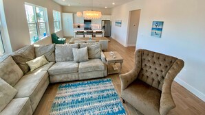 A spacious living area with a sectional sofa, a tufted armchair, and a dining table. - Nautical Nest in Fort Myers Beach (Fort Myers Beach)