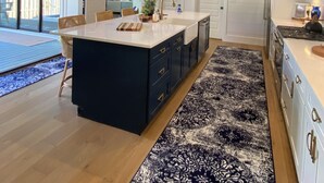 A modern kitchen with a central island, pendant lights, and a patterned rug. - Beach Bum Luxury 30A, Heated Pool, Golf Cart, Bikes, 3 Minute Walk to The Beach! (Santa Rosa Beach)