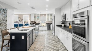 Una cocina moderna con armarios blancos, electrodomésticos de acero inoxidable y una isla central.