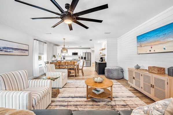 A spacious living room with striped sofas, a wooden coffee table, and a ceiling fan.