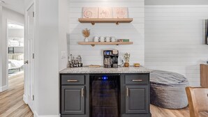 Una cocina moderna con armarios oscuros, horno empotrado, cafetera y objetos decorativos sobre la encimera.