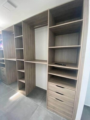 A modern closet with multiple shelves and drawers, featuring a light wood finish and a neutral color palette.