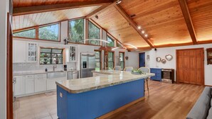 Un'ampia cucina con un'isola grande, soffitto in legno ed ampie finestre.