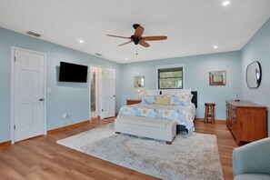 A bedroom with a bed, a ceiling fan, a television, a dresser, and a window. - River House with Dock, Waterfront Stunner Sunrise to Sunset (St Johns)