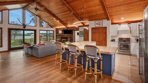 Una cucina spaziosa con una grande isola, soffitto in legno e sgabelli da bar.