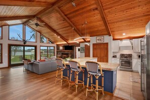 A spacious kitchen with a large island, bar stools, and a view of the outdoors. - River House with Dock, Waterfront Stunner Sunrise to Sunset (St Johns)