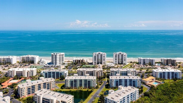 A coastal residential area with multiple high-rise buildings, a beach, and a clear view of the ocean.