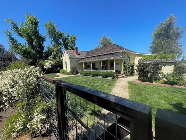 A two-story house with a front porch, a small garden, and a fenced backyard.