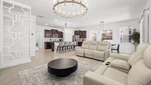 A spacious living room with a round coffee table, a beige sofa, and a chandelier. - Spacious 6-bedroom 5.5 baths Sleeps 16 with a Private Heated Pool/Spa (Davenport)