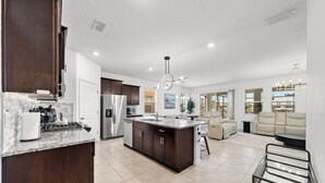 A spacious kitchen with dark wood cabinets, a granite countertop, and stainless steel appliances. - Spacious 6-bedroom 5.5 baths Sleeps 16 with a Private Heated Pool/Spa (Davenport)