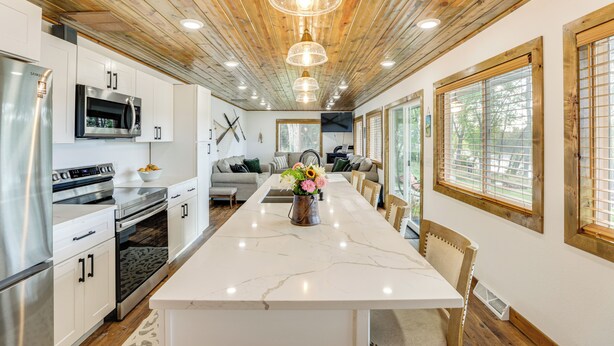 A modern kitchen with stainless steel appliances, a marble island, and wooden ceiling beams. - Riverfront Home w/ Private Dock in Wisconsin Dells (Wisconsin Dells)