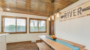 A kitchen with wooden flooring, a long table with a blue bench, and a wall sign reading "RIVER". - Riverfront Home w/ Private Dock in Wisconsin Dells (Wisconsin Dells)