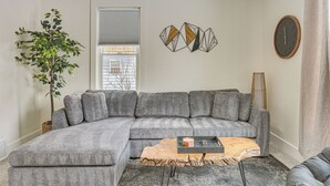 A modern living room with a grey sectional sofa, a wooden coffee table, and a decorative wall piece. - 3 Mi to Downtown Youngstown: Updated Apartment (Youngstown)