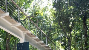 An outdoor dining area with wooden tables and chairs, surrounded by lush greenery and trees. - A Peaceful, Tropical Loft in the heart of the Riviera Maya (TLM Akumal)