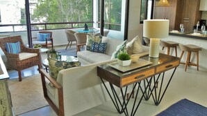 A modern living room with a sofa, chairs, a coffee table, and a dining area with stools. - A Peaceful, Tropical Loft in the heart of the Riviera Maya (TLM Akumal)