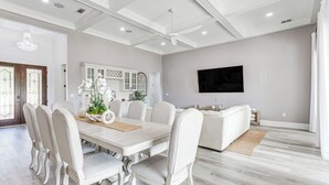 A spacious dining area with a white table and chairs, a ceiling fan, and a mounted TV on the wall. - Waterfront Retreat w/ Outdoor Oasis in Pensacola (Pensacola)