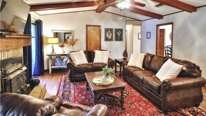 A spacious living room with a high ceiling, leather sofas, a coffee table, and a red patterned rug.