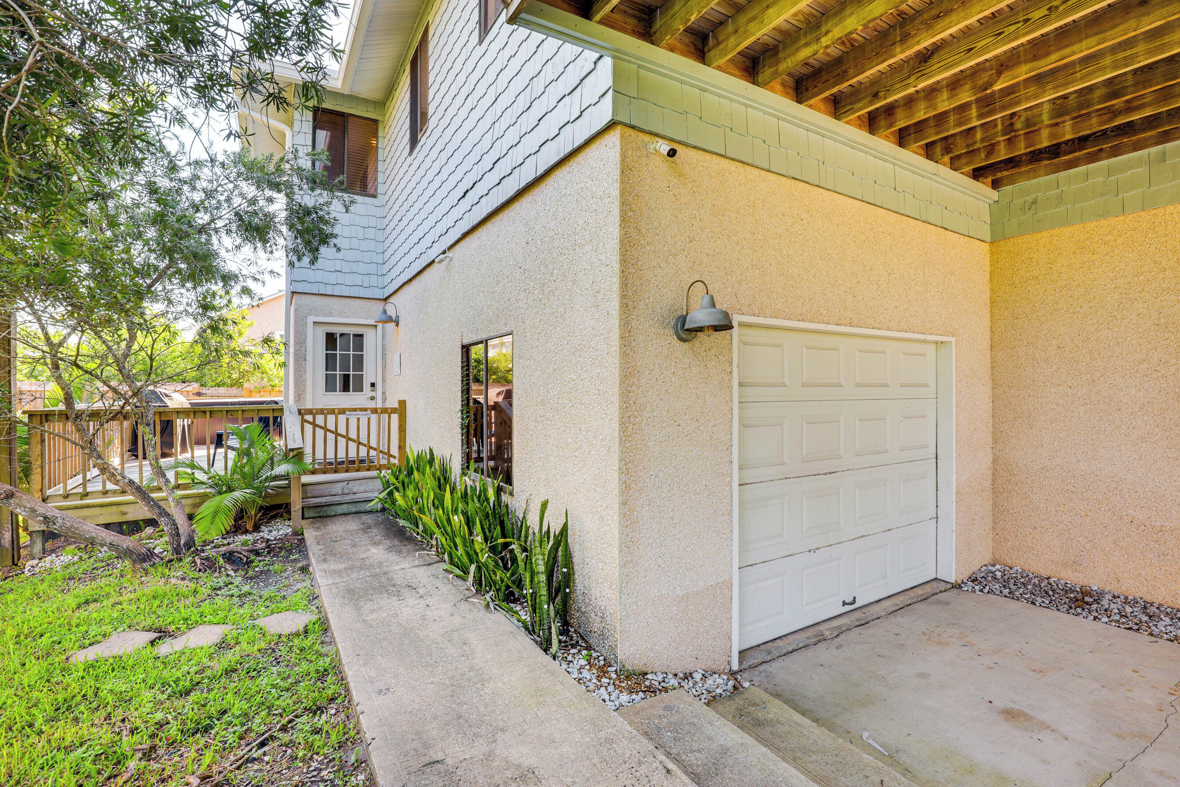 A residential garage with a white door, a small porch with a railing, and a concrete driveway.