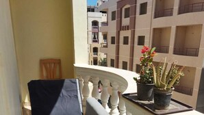 Ein Balkon mit Bett, Topfpflanzen und Blick auf die Nachbargebäude.