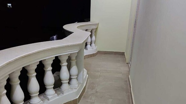 Ein gebogener Balkon mit weißen Geländern und einem gefliesten Boden.
