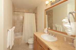 Un baño con bañera, inodoro, lavabo y un espejo grande.