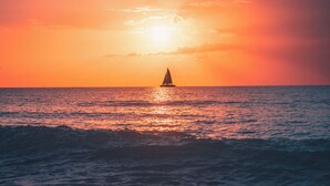 Un coucher de soleil sur l’océan, avec un bateau à l’horizon.