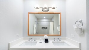 Une salle de bain avec deux lavabos, un grand miroir et un porte-serviettes.