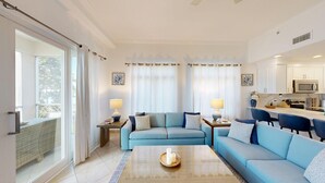 A modern living room with a sofa set, a coffee table, and a kitchen area with a microwave and stove.