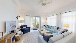 A spacious living room with a television, two sofas, a coffee table, and a ceiling fan.